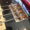 Close-up of vintage guitar bridge and strings on black electric guitar body with visible wear and scratches