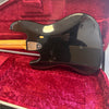 Black electric guitar body with visible wear and scratches on a red velvet-lined case interior, showing the neck plate with Fender logo.