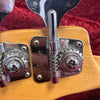 Close-up of chrome tuning pegs on a Fender guitar headstock with natural wood finish and red velvet background