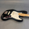 Black electric bass guitar with white pickguard and maple fretboard on gray background