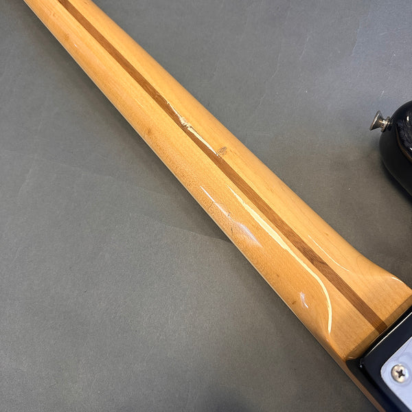 Glossy maple guitar neck with walnut skunk stripe detail and black guitar body edge on gray background