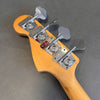 Fender bass guitar headstock with four vintage-style chrome tuning pegs on natural wood finish against gray background