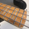 Close-up of maple guitar fretboard with metal frets and pearl rectangular inlays on electric bass guitar strings and white guitar body