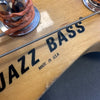 Close-up of Jazz Bass headstock with "Made in U.S.A." label and bass string, natural wood finish