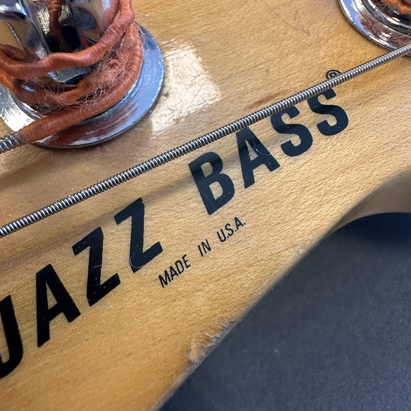 Close-up of Jazz Bass headstock with "Made in U.S.A." label and bass string, natural wood finish
