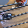 Close-up of bass guitar strings wound tightly around tuning pegs on light wood headstock.