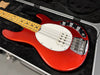 Red electric bass guitar with maple neck and white pickguard in black hardshell case
