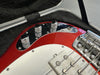 Close-up of red electric bass guitar control knobs, pickup, and bridge inside a black padded guitar case