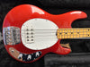 Red electric bass guitar with white pickguard, maple fretboard, and chrome hardware on black plush case interior