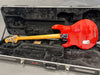 Red electric bass guitar with flame maple neck lying inside black plush-lined hard case labeled Music Man StingRay, showing back and tuning pegs.