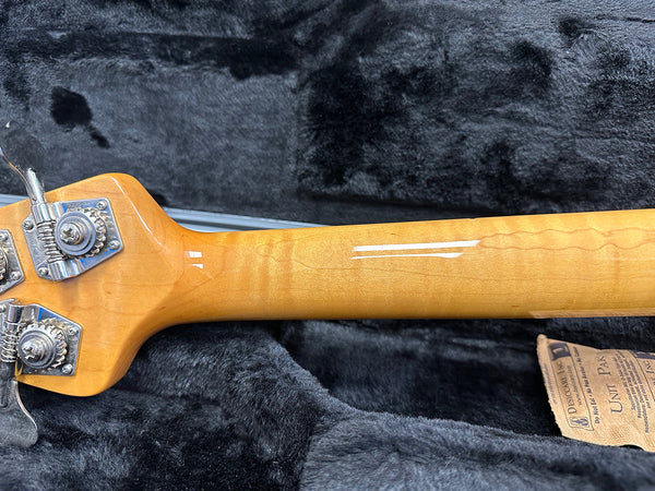 Close-up of maple neck with tuning pegs and gear mechanism on electric bass guitar resting on black plush guitar case lining