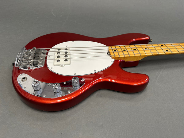 Red electric bass guitar with maple neck and white pickguard on gray background