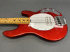 Red finish electric bass guitar with maple neck, white pickguard, chrome control knobs, and single humbucker pickup on gray background.