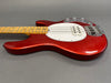 Red electric bass guitar with maple neck and white pickguard on grey background