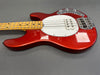 Red electric bass guitar with white pickguard and maple neck on gray background