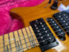 Close-up of honey burst electric guitar body and maple neck with black humbucker pickups and tone control knob on pink plush background