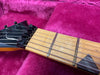 Close-up of electric guitar headstock and maple fretboard with metal frets and strings on a plush pink case interior
