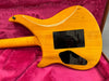 Back view of orange electric guitar body with two black plastic cover plates, resting on a pink plush guitar case interior