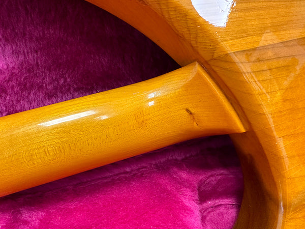 Close-up of glossy wooden guitar neck heel joint on purple plush guitar case interior
