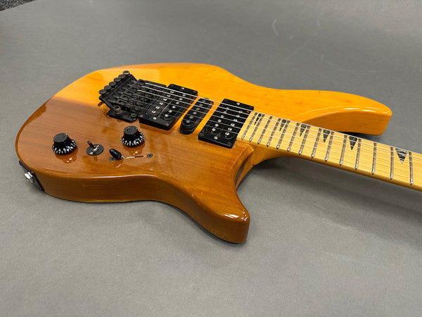 Natural finish electric guitar with black humbucker pickups and maple neck featuring triangle inlays on fretboard