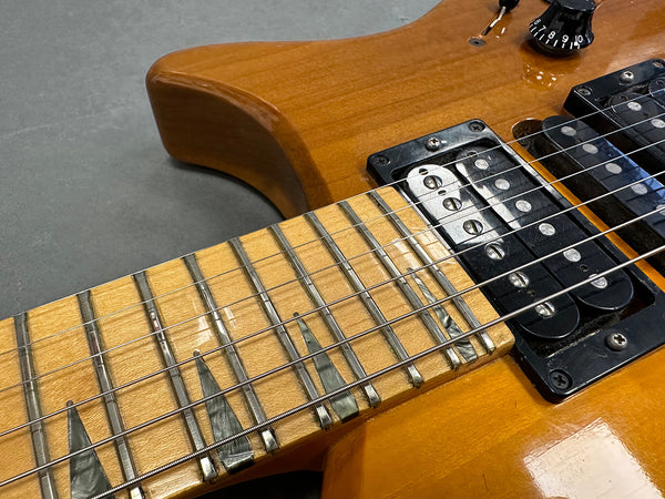 Close-up of electric guitar with amber finish showing maple fretboard with unique pearl inlays and humbucker pickups from Coffee House Guitars