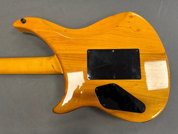 Back view of a yellow electric guitar showing the wood grain and black plastic access panels on a gray background