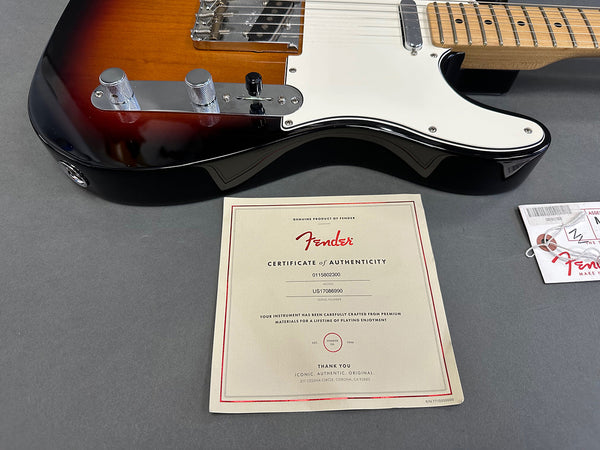 Fender electric guitar body close-up with certificate of authenticity and Fender hang tag on gray surface
