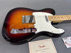 Fender Telecaster electric guitar in sunburst finish with maple neck and white pickguard, Fender certificate of authenticity and tags on gray surface