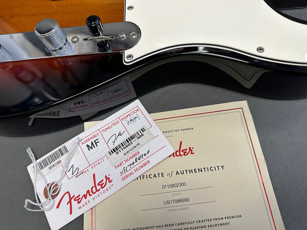 Close-up of Fender guitar control knobs, assembly tag, and certificate of authenticity with serial number and model details.