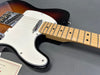 Close-up of sunburst Fender Telecaster electric guitar body and maple neck with white pickguard on gray background at Coffee House Guitars