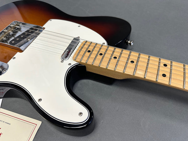 Close-up of sunburst Fender Telecaster electric guitar body and maple neck with white pickguard on gray background at Coffee House Guitars