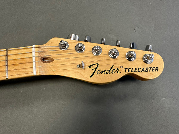 Close-up of Fender Telecaster guitar headstock with chrome tuning pegs on gray background