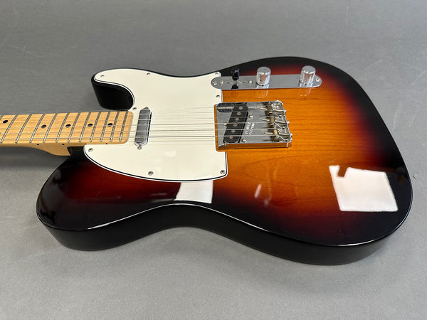 Close-up of vintage sunburst electric guitar body with white pickguard and chrome bridge on gray background