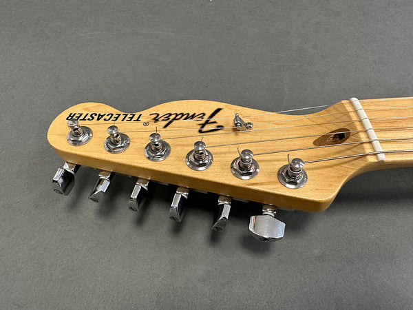 Close-up of Fender Telecaster electric guitar headstock with tuning pegs and strings on a gray background