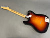 Back view of sunburst electric guitar with maple neck and six tuning pegs on gray background