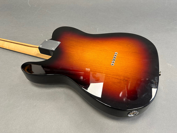 Electric guitar body with sunburst finish and string ferrules, maple neck visible, against gray background