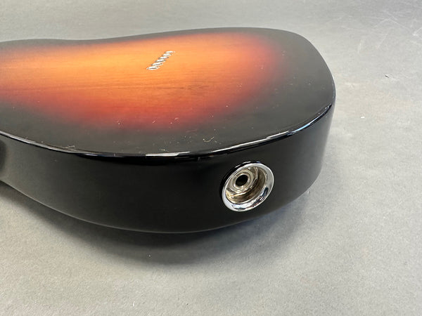 Close-up of sunburst electric guitar body showing the output jack on a gray background