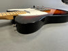 Electric guitar close-up side view with sunburst finish, maple neck, and chrome hardware on gray background