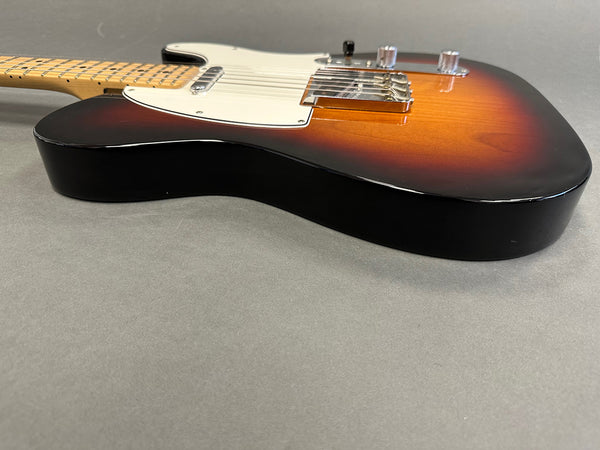 Sunburst finish electric guitar body with white pickguard and chrome bridge on gray background