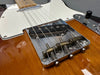 Close-up of vintage Fender Telecaster electric guitar bridge with chrome saddles and single coil pickup on amber wood finish body