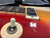 Close-up of red electric guitar body showing toggle switch, pickup, and fretboard details with wood grain finish