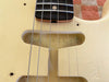Close-up of vintage Fender-style electric guitar body with cream relic finish and visible text "64 RELIC" in pickup cavity under strings and part of rosewood fretboard.