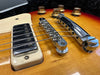 Close-up of vintage electric guitar bridge, pickup, and volume knobs on sunburst finish body in guitar case