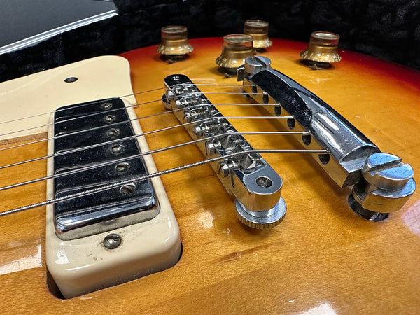 Close-up of vintage electric guitar bridge, pickup, and volume knobs on sunburst finish body in guitar case