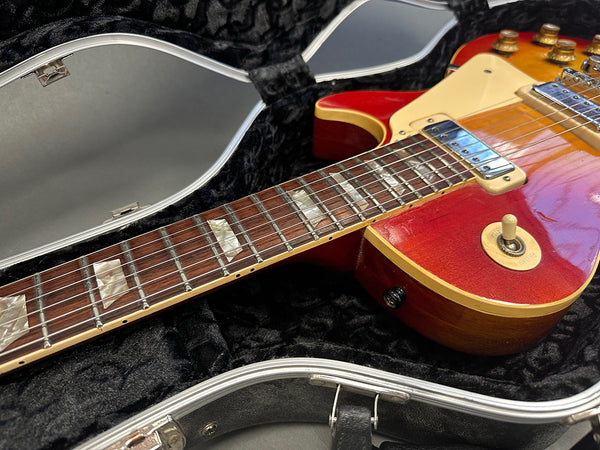 Close-up view of red electric guitar with cream pickguard and toggle switch inside black padded hard case