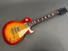 Gibson Les Paul electric guitar in sunburst finish with cream pickguard and chrome hardware on gray background