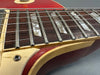Close-up of vintage electric guitar fretboard with pearl inlays, metal frets, aged binding, and red body showing wear and patina