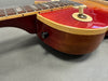 Close-up of cherry sunburst electric guitar body with cream binding and switch toggle on gray background