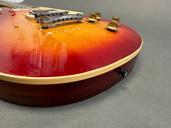 Close-up view of sunburst electric guitar body featuring chrome bridge and gold control knobs on gray background