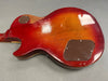 Back view of vintage red burst electric guitar body with worn finish and plastic control cavity covers on gray background